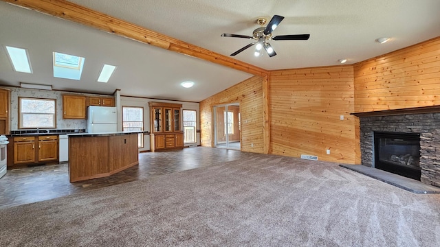 kitchen with dark colored carpet, a fireplace, white appliances, and vaulted ceiling with skylight