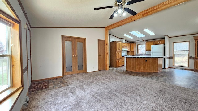 kitchen featuring ceiling fan, white refrigerator, a breakfast bar, carpet, and vaulted ceiling with skylight