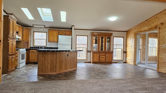 kitchen with plenty of natural light, wood walls, a kitchen breakfast bar, and white appliances