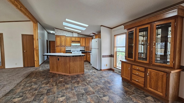 kitchen with a center island, white appliances, a textured ceiling, and lofted ceiling with skylight