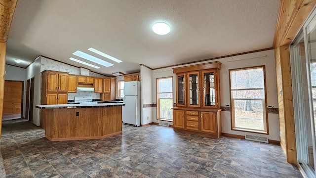 kitchen featuring a kitchen breakfast bar, a textured ceiling, white appliances, vaulted ceiling with skylight, and ornamental molding