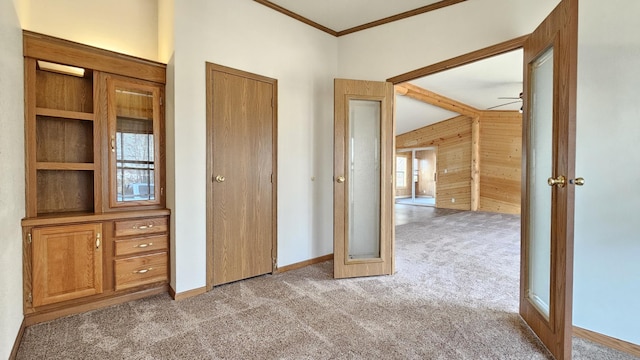 unfurnished bedroom with light carpet, crown molding, and wooden walls