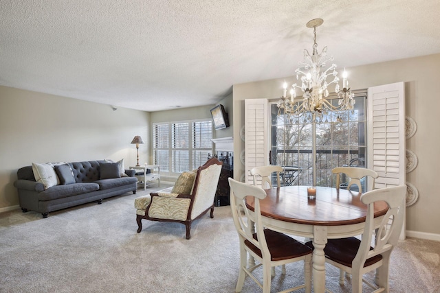 dining area with baseboards, light colored carpet, a textured ceiling, a fireplace, and a notable chandelier