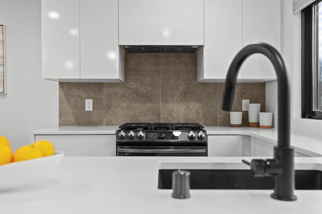 interior details with extractor fan, black gas range, tasteful backsplash, and white cabinetry