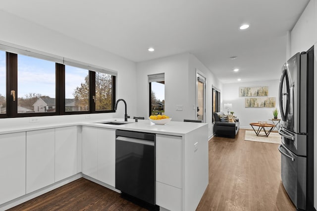 kitchen with dark wood-type flooring, white cabinets, sink, appliances with stainless steel finishes, and kitchen peninsula