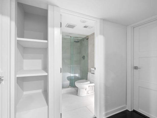 bathroom featuring tile patterned flooring, toilet, and an enclosed shower