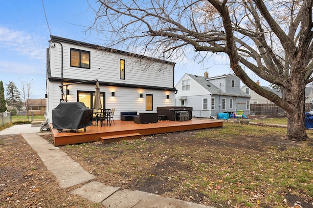 back of house featuring a jacuzzi and a wooden deck