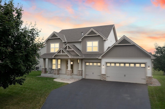 craftsman inspired home with aphalt driveway, covered porch, a garage, stone siding, and a front lawn