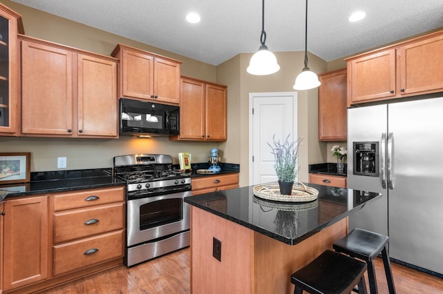 kitchen with stainless steel appliances, glass insert cabinets, light wood-style floors, a kitchen island, and a kitchen breakfast bar