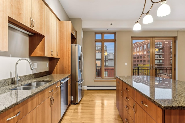 kitchen featuring sink, pendant lighting, dark stone counters, and light wood-type flooring