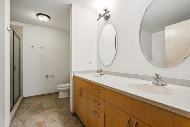 bathroom with double vanity, a sink, toilet, and a shower stall