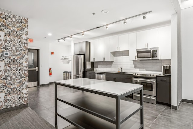 kitchen with light tile patterned floors, tasteful backsplash, appliances with stainless steel finishes, white cabinets, and a sink