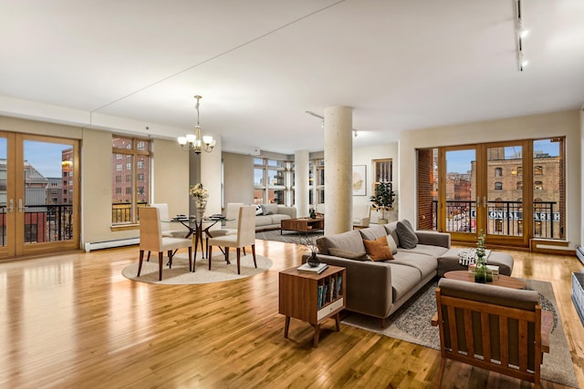 living area with a chandelier, a baseboard radiator, a city view, wood finished floors, and track lighting