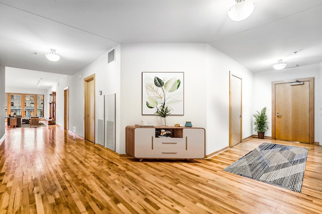 hall with baseboards, visible vents, and wood finished floors