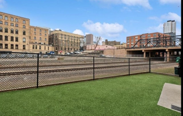 view of tennis court with a city view and fence