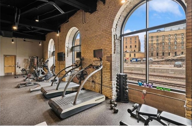 gym featuring a view of city, brick wall, plenty of natural light, and a towering ceiling