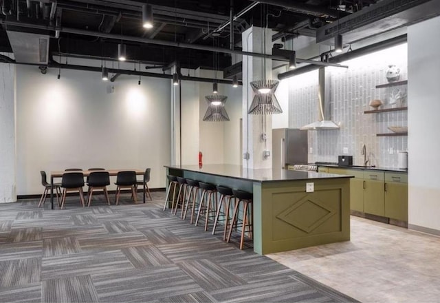 interior space featuring light carpet, a high ceiling, green cabinets, freestanding refrigerator, and dark countertops