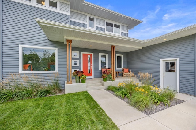 doorway to property featuring a porch and a lawn