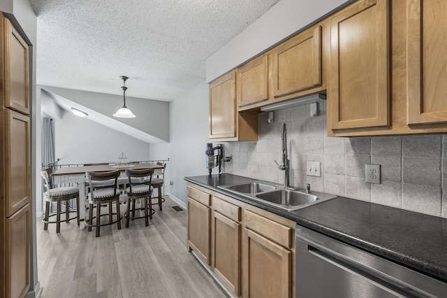 kitchen featuring tasteful backsplash, sink, dishwasher, light hardwood / wood-style floors, and hanging light fixtures