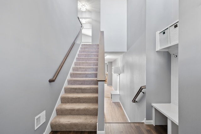 stairs featuring a towering ceiling and wood-type flooring