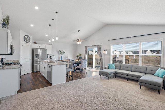 living room with dark hardwood / wood-style flooring, ceiling fan, sink, and vaulted ceiling