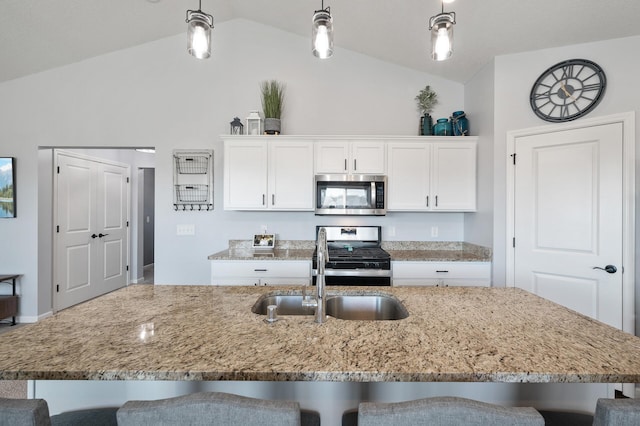 kitchen featuring stainless steel appliances, lofted ceiling, sink, a breakfast bar area, and pendant lighting