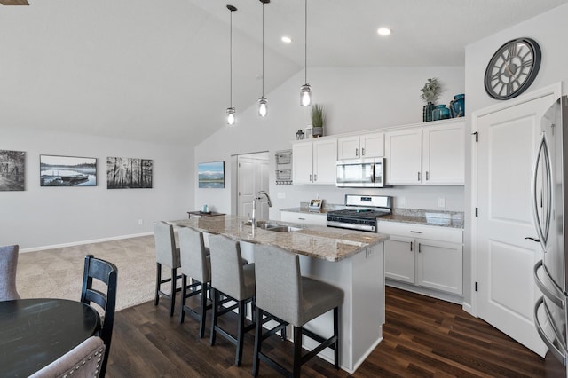 kitchen featuring stainless steel appliances, white cabinetry, sink, light stone counters, and decorative light fixtures