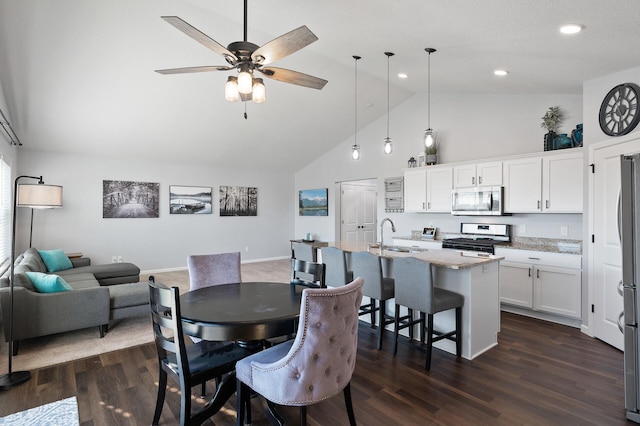 dining room featuring dark wood-type flooring, ceiling fan, sink, and high vaulted ceiling