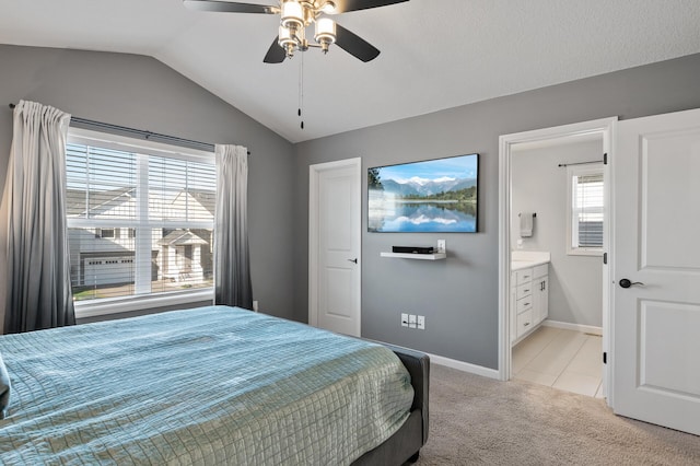 bedroom featuring vaulted ceiling, light carpet, ceiling fan, and ensuite bath