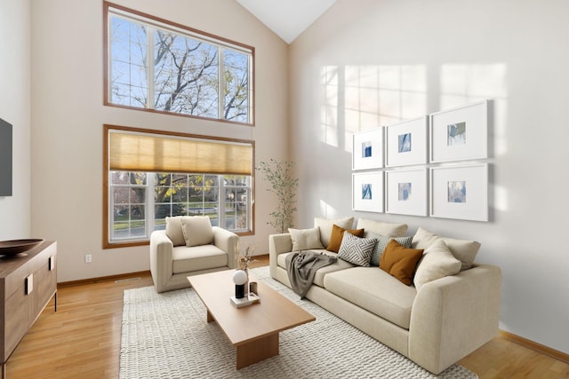 living room featuring high vaulted ceiling, light hardwood / wood-style flooring, and a healthy amount of sunlight