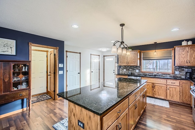 kitchen featuring dark hardwood / wood-style floors, dark stone countertops, decorative light fixtures, decorative backsplash, and a kitchen island