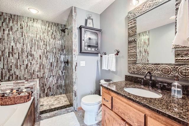 bathroom with vanity, toilet, a textured ceiling, and a tile shower