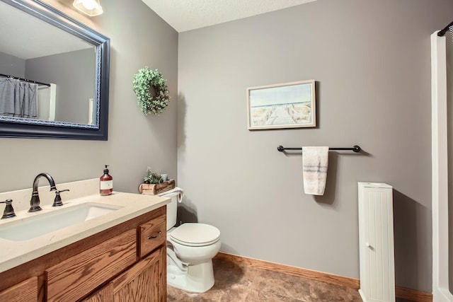 bathroom featuring a textured ceiling, vanity, and toilet