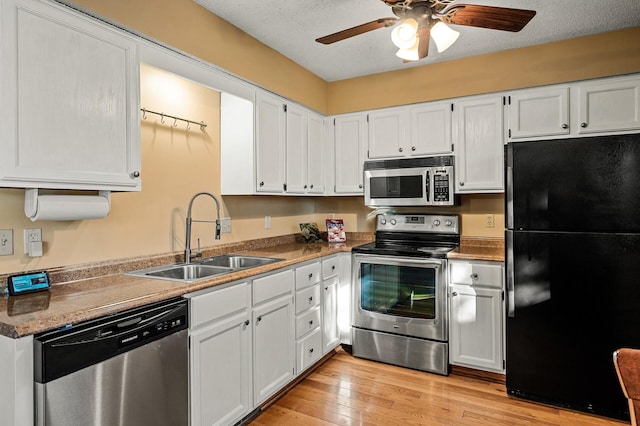 kitchen with stainless steel appliances, white cabinets, sink, and light wood-type flooring