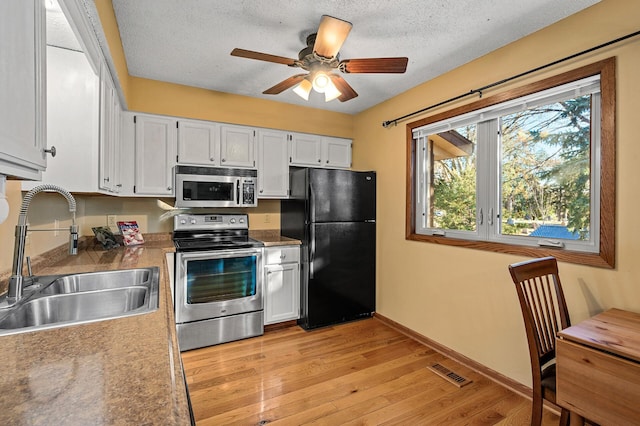 kitchen with white cabinetry, appliances with stainless steel finishes, sink, and light hardwood / wood-style flooring