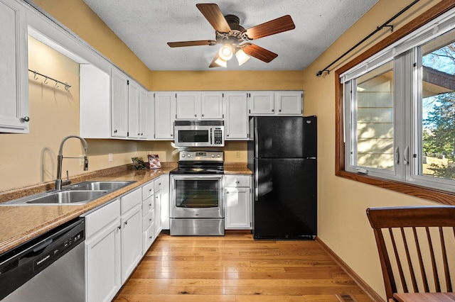 kitchen featuring light hardwood / wood-style floors, a textured ceiling, sink, white cabinetry, and appliances with stainless steel finishes