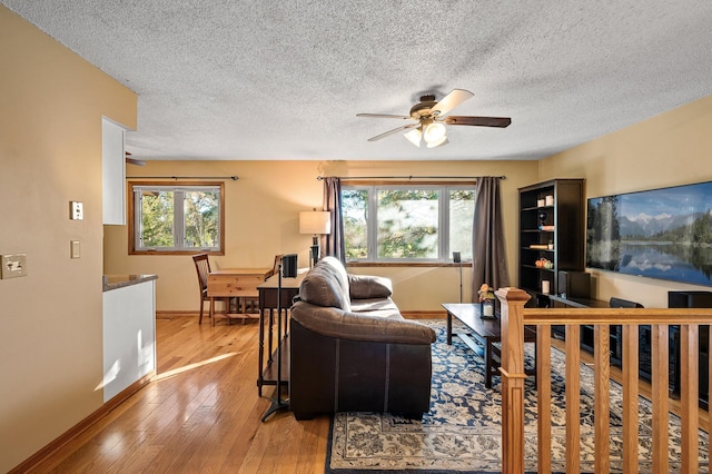 living room with a wealth of natural light, a textured ceiling, and light hardwood / wood-style floors