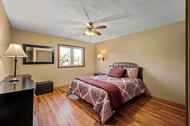 bedroom with a textured ceiling, light hardwood / wood-style flooring, and ceiling fan