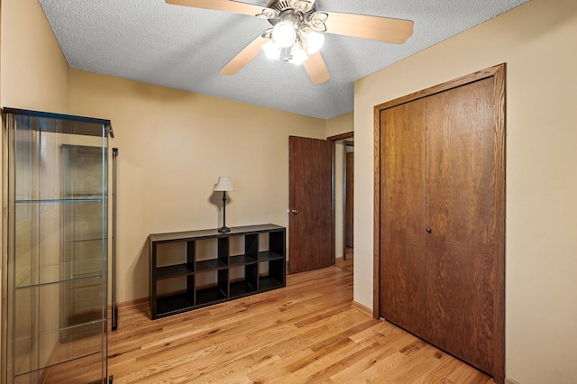 bedroom featuring ceiling fan, a textured ceiling, a closet, and light hardwood / wood-style flooring