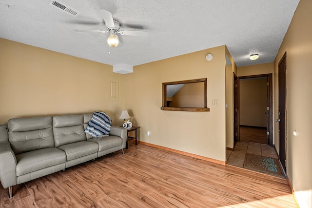 living room featuring light hardwood / wood-style flooring, a textured ceiling, and ceiling fan