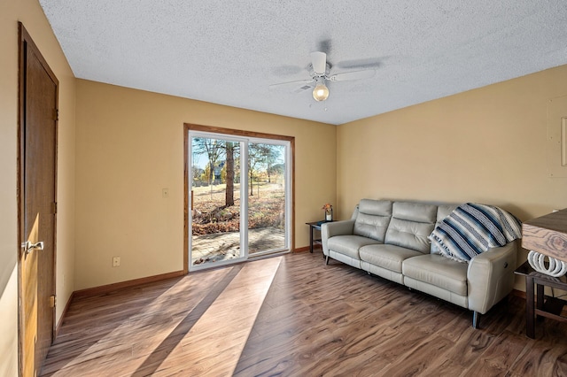 living room with hardwood / wood-style flooring, ceiling fan, and a textured ceiling