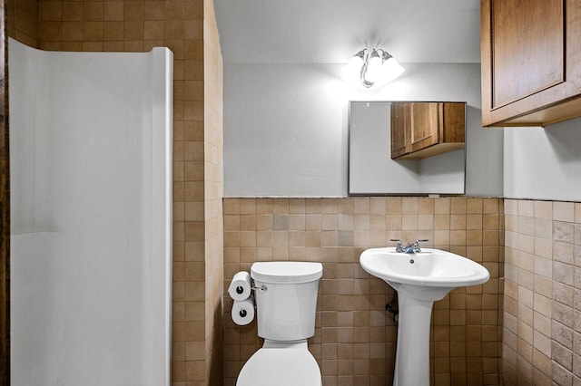 bathroom featuring toilet and tile walls