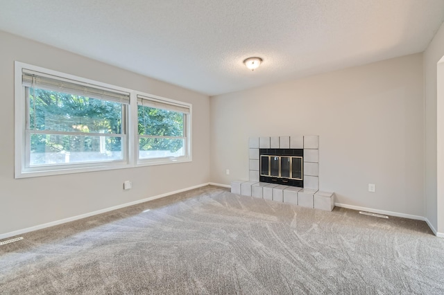 unfurnished living room with a fireplace, carpet floors, and a textured ceiling