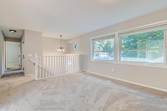 carpeted empty room featuring an inviting chandelier