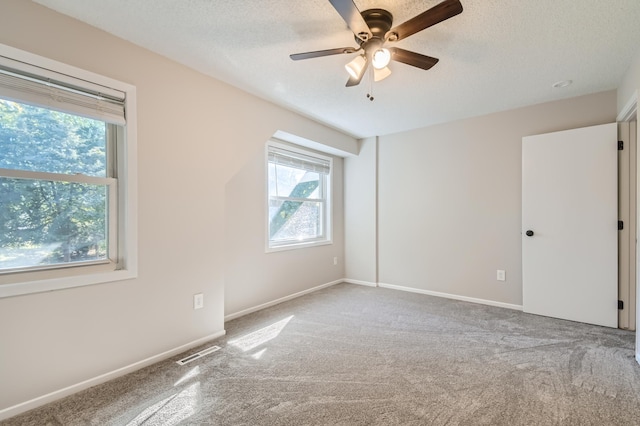 empty room featuring plenty of natural light, ceiling fan, and carpet floors