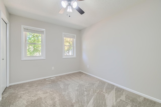 carpeted spare room with ceiling fan and a textured ceiling