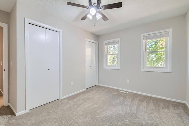 unfurnished bedroom featuring ceiling fan, light colored carpet, and a textured ceiling