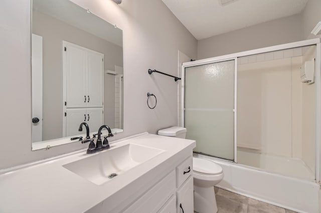 full bathroom with tile patterned floors, bath / shower combo with glass door, vanity, a textured ceiling, and toilet