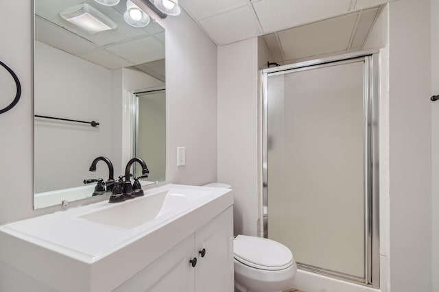 bathroom featuring an enclosed shower, vanity, toilet, and a drop ceiling