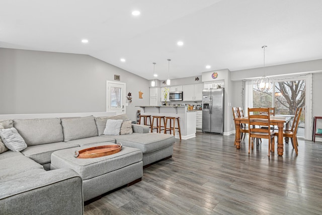 living room with an inviting chandelier, vaulted ceiling, and dark wood-type flooring